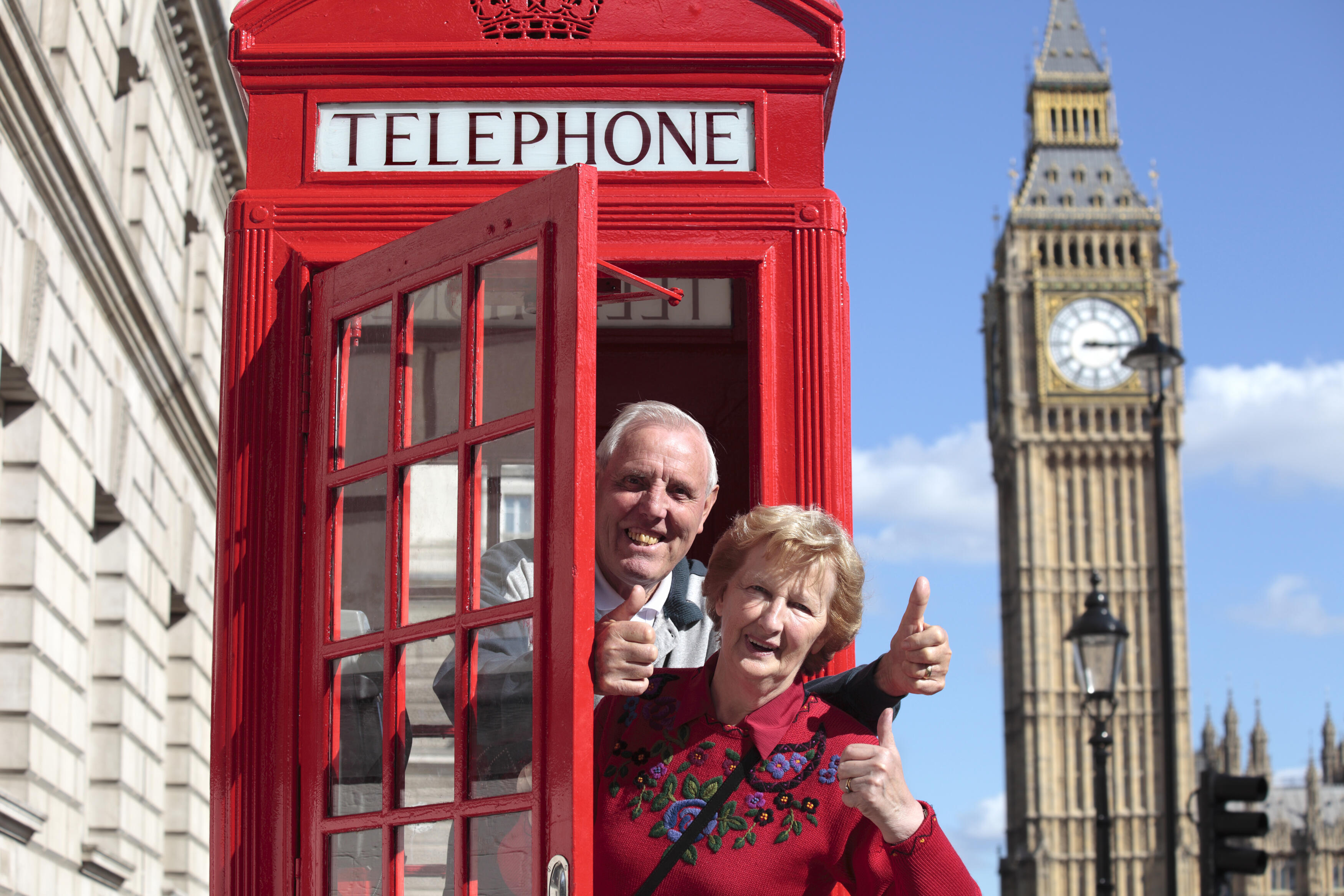 Senior couple with red telephone box in London. Big Ben in the background.